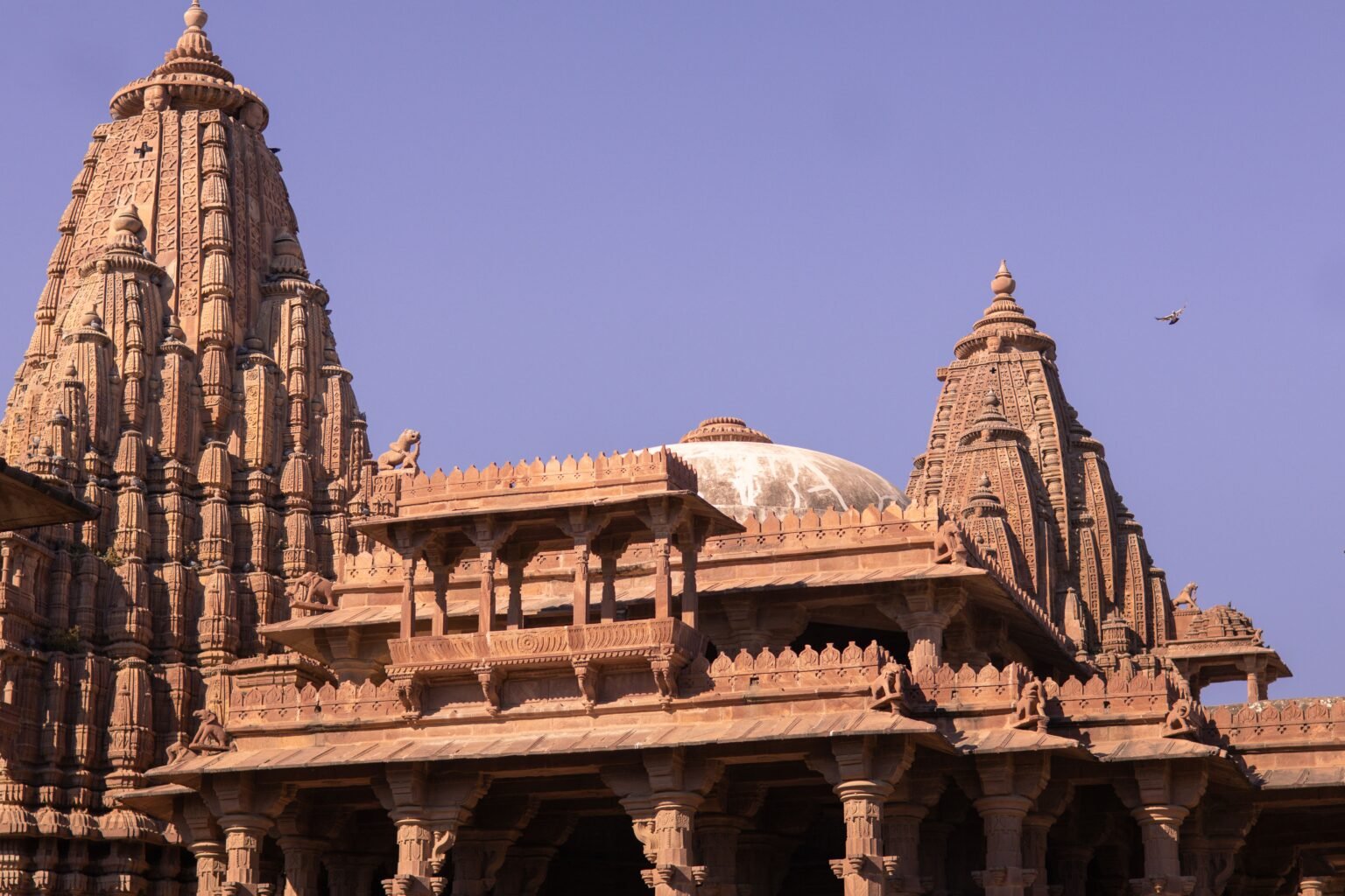A beautifully intricate Indian temple captured under a clear blue sky, showcasing stunning architectural detail.