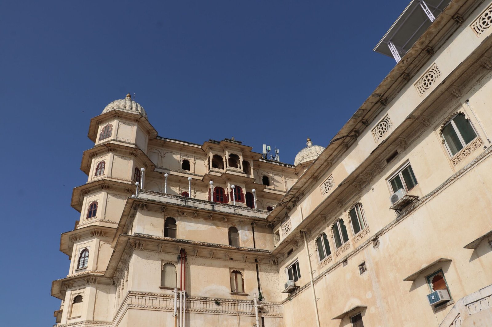 Angled view of the historic City Palace against a clear blue sky, Udaipur, India.